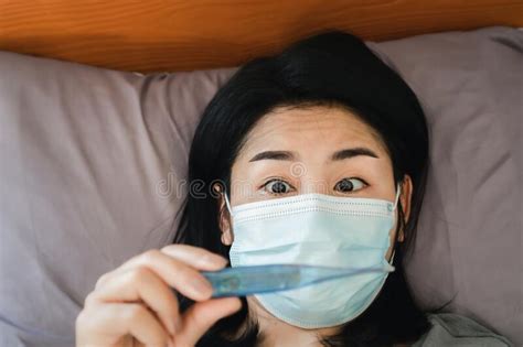 Shocked Asian Woman Checking Her High Temperature By Thermometer In Bed