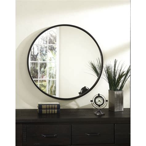 A Round Mirror Sitting On Top Of A Dresser Next To A Potted Plant And Books
