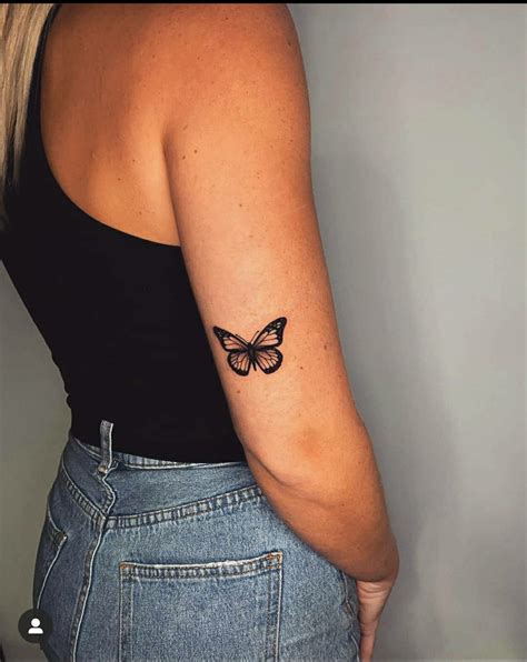 A Woman With A Butterfly Tattoo On Her Left Arm And The Back Of Her