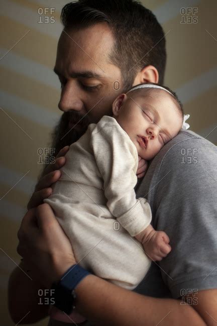 Newborn Baby Girl Sleeping On Fathers Shoulder At Home In Soft Light