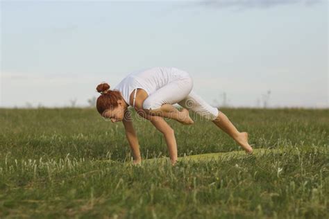 Young Female Doing Balancing Exercise While Practising Yoga On Green