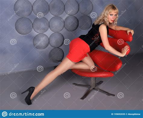 Blonde Model In Stockings And Red Miniskirt Posing In Studio Stock