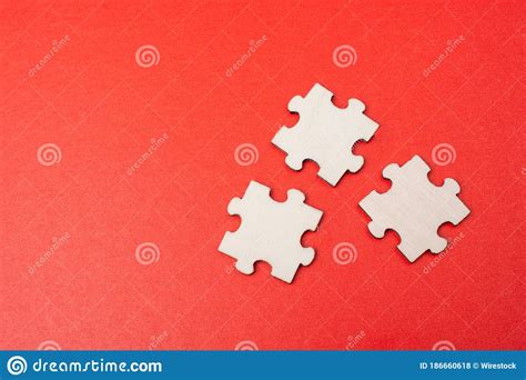 Closeup Shot Of Blank Puzzle Pieces On A Red Table Under The Lights