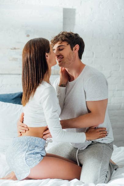 Young Woman In Pajamas Kissing Boyfriend On Bed Free Stock Photo And Image