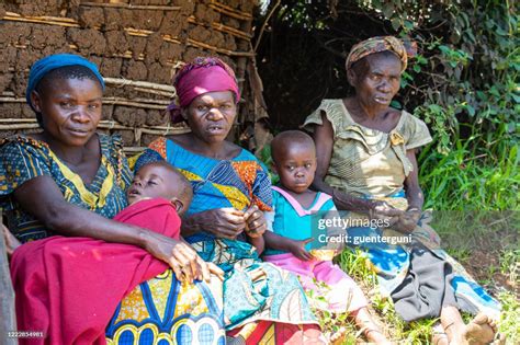 Women Of The Batwa Pygmy Sitting In Front Of Their Hut High Res Stock