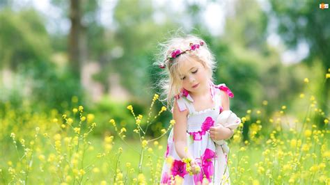 Dziewczynka z wiankiem wśród kwiatów na łące