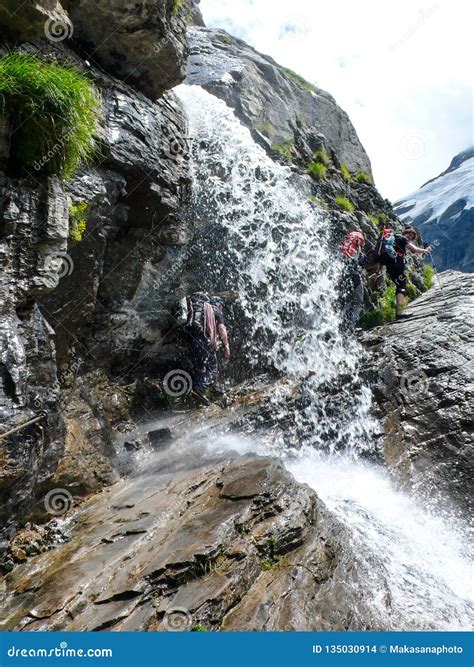 Mountain Climbers Hiking Under A Waterfall On A Rocky Hiking Trail