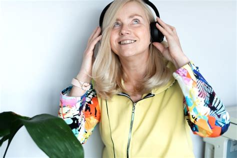 Premium Photo Dreamy Middle Aged Blonde Woman Listening To Music Through Headphones