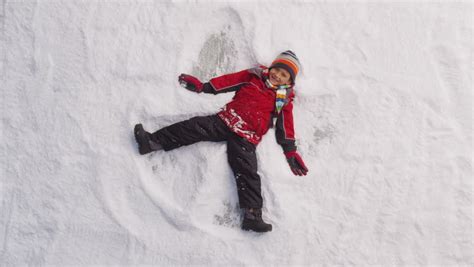 Young Boy Making Snow Angel In Winter Stock Footage Video