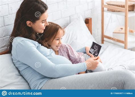 Expecting Woman Showing Ultrasound Scan To Her Daughter Stock Image
