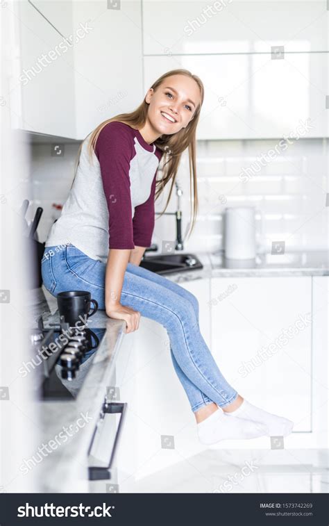 Young Woman Sitting On Kitchen Counter Stock Photo 1573742269