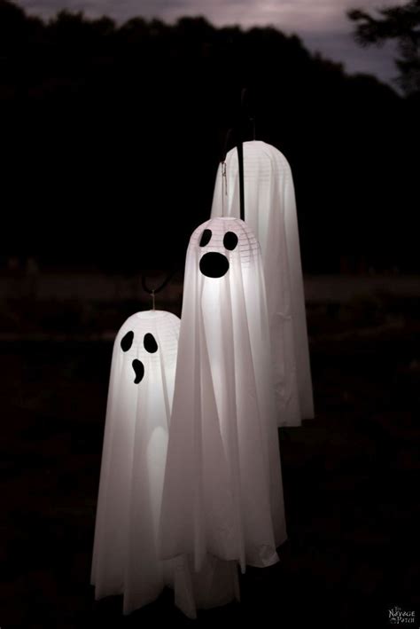 Three Ghost Lanterns Hanging In The Dark With Faces Drawn On Them And