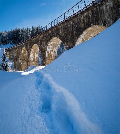 Stone Viaduct Arch Bridge On Railway Through Mountain Snowy Fir Forest