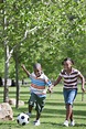 African American children playing soccer in park - Stock Photo - Dissolve