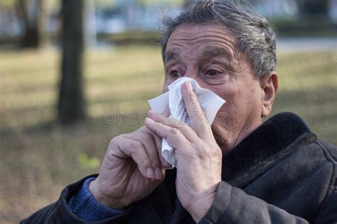 Portrait Of A Coughing Senior Man Outdoors Looking Down Stock Photo