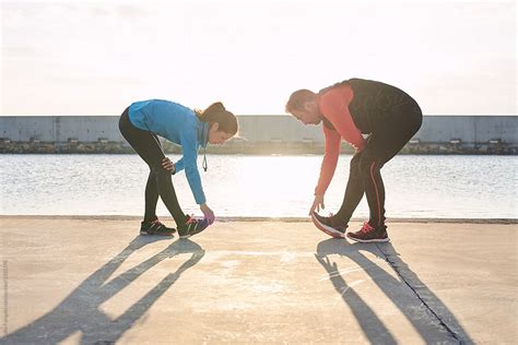 Sportive Couple Stretching Legs On Pier By Stocksy Contributor Guille Faingold Stocksy
