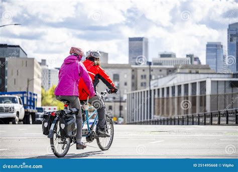 Two Amateur Cyclists Wearing Colorful Jackets Are Cycling On A Tandem Bike Through The Streets