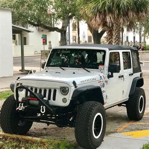 A White Jeep Is Parked On The Side Of The Road In Front Of Some Palm Trees