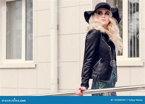 Girl In A Black Hat And A Leather Jacket Walks Through The City Stock