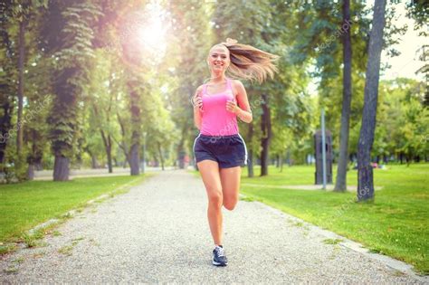 mulher saudável e feliz correndo no parque urbano com fones de ouvido