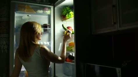 Sexy Woman Opens The Refrigerator At Night Selects A Cucumber Stock