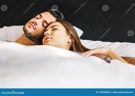 Loving Young Couple Sleeping Together In A Bed With White Sheets At