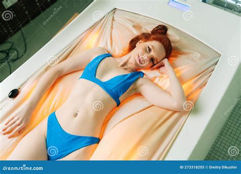 Top View Of Pretty Young Woman Wearing Bikini Lying On Electric Massage Bed Having Rest