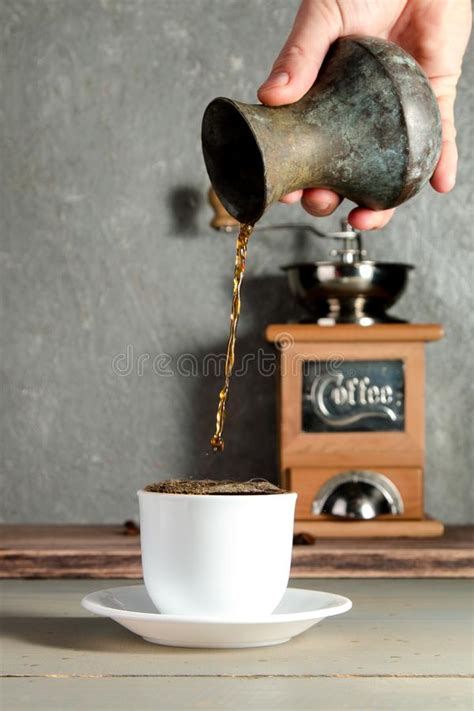 Men Hand Pouring A Cup Of Coffee Creating Splash On Wooden Background
