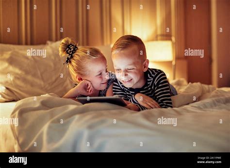 Cute Little Brother And Sister Laughing While Lying On A Bed Together