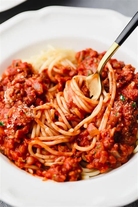 A White Bowl Filled With Spaghetti And Sauce