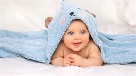 Smiling Grey Eyes Cute Child Baby Is Lying Down On White Cloth Covered