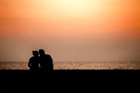 couple silhouette cuddling and watching sun at sunset on the beach couple silhouette sunset