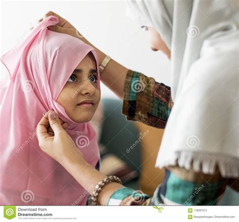Muslim Mother Putting On A Hijab On Her Little Daughter Stock Image