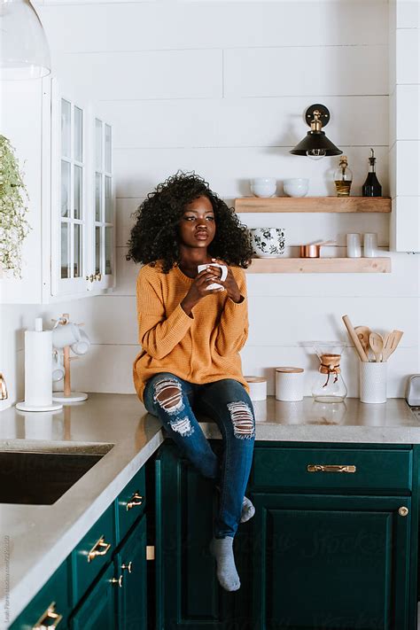 Woman Sitting On Kitchen Counter With Coffee Mug Del Colaborador De Stocksy Leah Flores