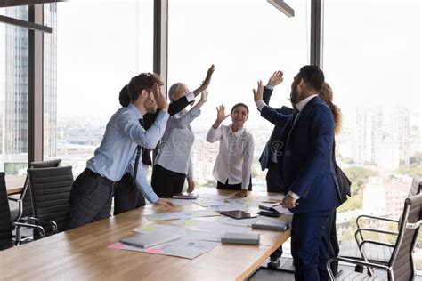 Excited Business Colleagues Giving Group High Five Over Meeting Table