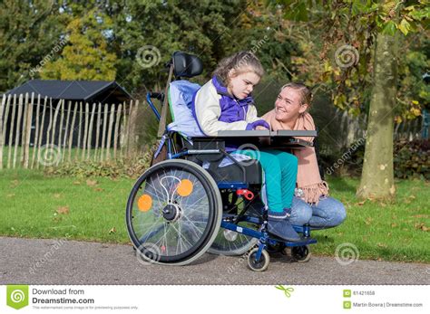 A Disabled Girl In A Wheelchair Outside With A Care