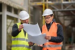 Young Asian apprentice at work on construction site with senior ...