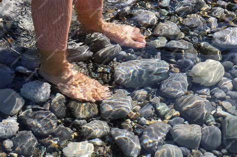 Premium Photo Male Bare Feet In Water On Underwater Stones With