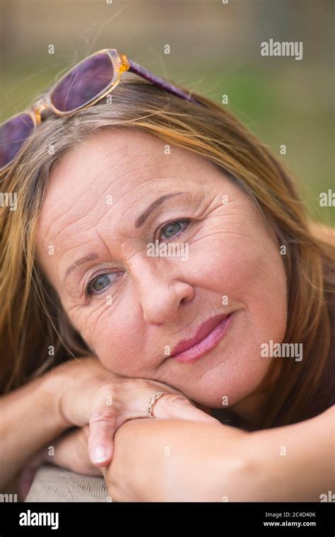 portrait attractive mature woman posing relaxed and happy smiling outdoor with sunglasses green