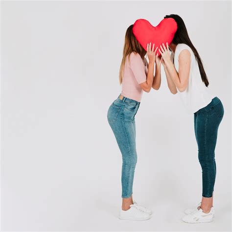 Bonita pareja de lesbianas besándose detrás de corazón Foto Gratis