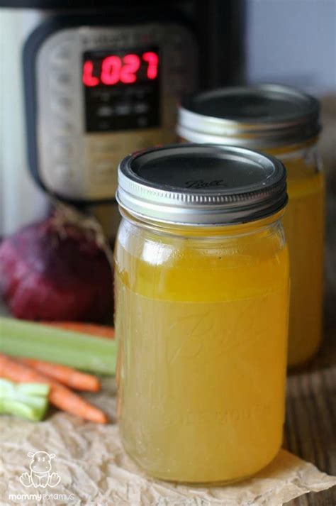 Two Mason Jars Filled With Yellow Liquid Next To Carrots And Celery