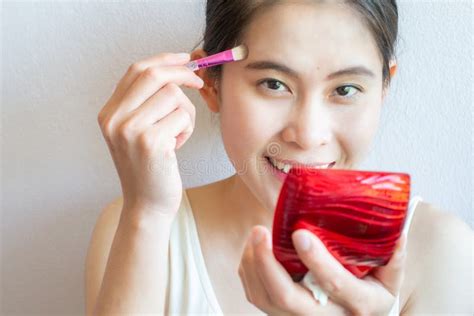 Portrait Of Happiness Asian Woman Applying Concealer On Her Facial Skin
