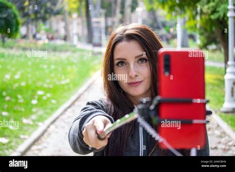 Pretty Attractive Brunette With Amber Orange Eyes In A Public Park Taking A Selfie With A Selfie