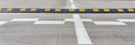 Black And Yellow Speed Bump Located On Grey Asphalt Road Stock Photo