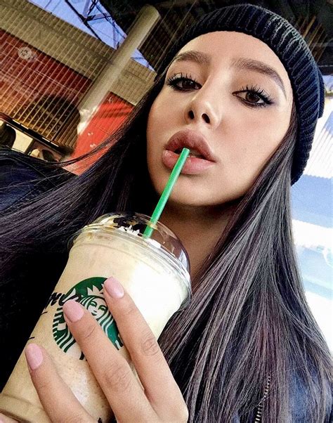 a woman holding a starbucks drink in her right hand and wearing a beanie hat