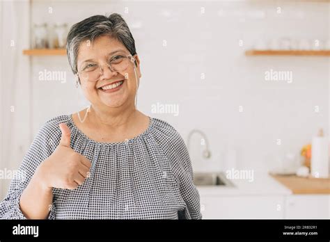 Portrait Happy Healthy Mature Asian Woman Smiling Cute Lovely At Home Kitchen Hand Thumbs Up