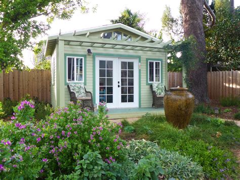 A Small Garden Shed In The Middle Of A Yard With Flowers And Trees