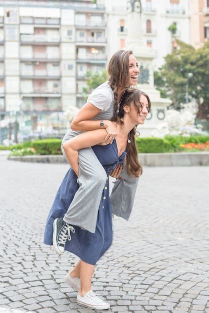 Free Photo Smiling Young Woman Taking Her Girlfriend Piggyback Ride