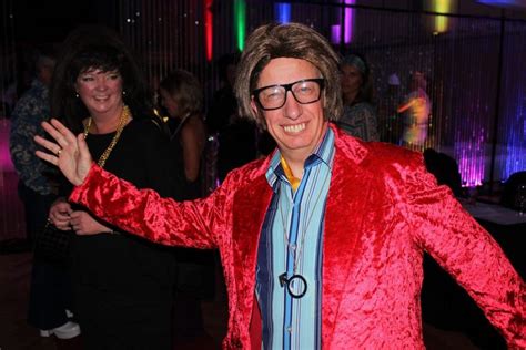 A Man In A Red Jacket And Glasses Dancing With His Arms Out To The Side