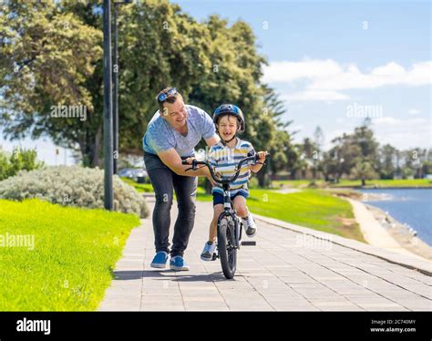 Niño Aprendiendo A Montar En Bicicleta Con Su Padre En El Parque Junto